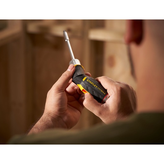 STANLEY FMHT0-62691 screwdriver with black and yellow handle held in hand, close-up side view.