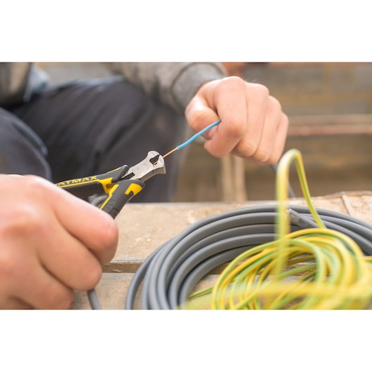 Stanley FMHT0-80519 diagonal pliers cutting wire, close-up photo during electrical work.