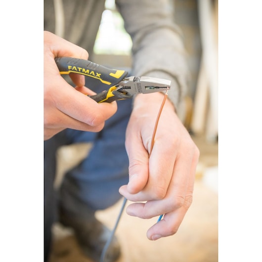 Stanley FMHT0-80541 pliers holding wire, close-up photo, tool being used for electrical work.