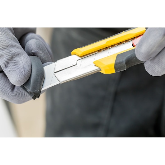 STANLEY FMHT10330-0 utility knife with segmented blade, yellow and black handle, close-up in use.