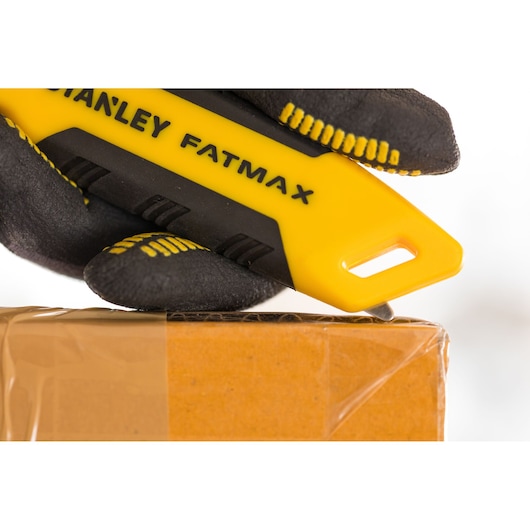 STANLEY FMHT10373-0 utility knife with yellow and black handle, cutting tape on a cardboard box, close-up.