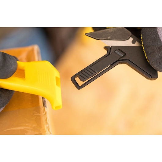 Photo of STANLEY FMHT10373-0 utility knife and yellow cutter tool close-up on cardboard box.