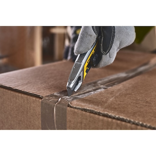 STANLEY FMHT10592-0 utility knife opening cardboard box, close-up view.