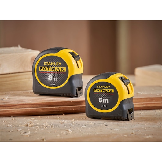 Photo of STANLEY FMHT31725-0 tape measures, yellow and black, on wooden surface, one 8m and one 5m model.