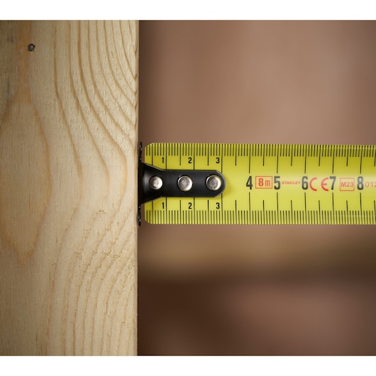 STANLEY FMHT31725-0 tape measure extended against wood, close-up view.