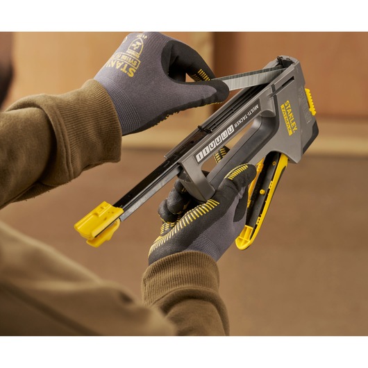 Stanley FMHT6-70868 multi-tacker being loaded with staples by gloved hands in workshop setting.