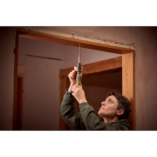 STANLEY FMHT62692-0 screwdriver held upright during door frame installation, yellow and black handle visible.