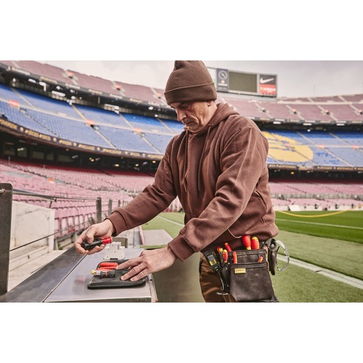 STANLEY FMHT66426-0 tool pouch with hand tools worn by worker in stadium, photo from side outdoors.