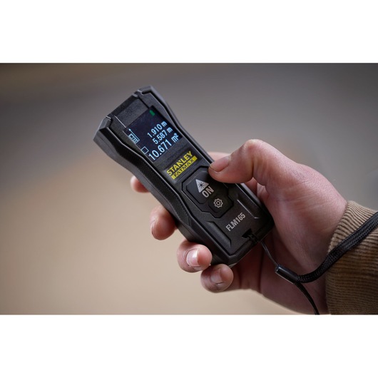 STANLEY FMHT77165-0 laser distance measurer held in hand, close-up view.