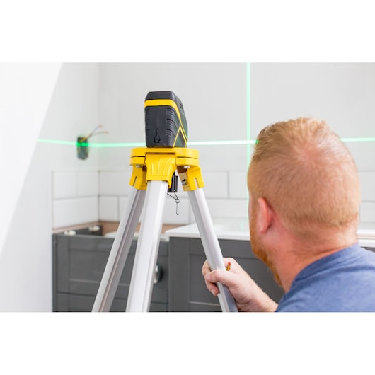 STANLEY FMHT77595-1 laser level on tripod in kitchen, green laser lines projected on wall.