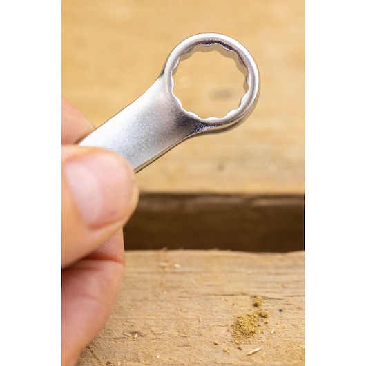 Close-up photo of STANLEY FMMT13039-0 box end wrench on wood surface, tool held by hand.