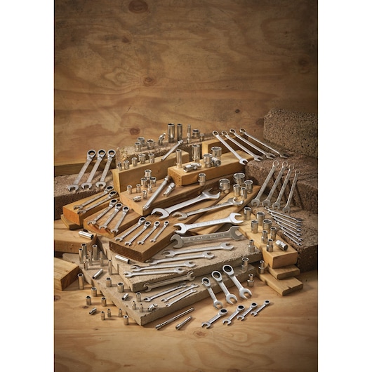 A collection of metal wrenches and sockets arranged on wooden blocks, displayed against a wooden background.