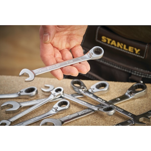 Photo of STANLEY FMMT13087-0 wrench set, silver wrenches on table, one held in hand, close-up angle.