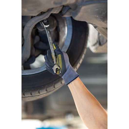 STANLEY FMMT13095-0 wrench used by gloved hand to tighten bolt under vehicle, close-up photography.