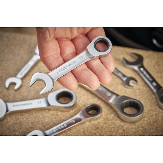 Photo of STANLEY FMMT13112-0 ratcheting spanners, close-up of hand holding a silver wrench, tools on work surface.
