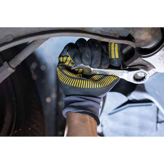 STANLEY FMMT13113-0 wrench being used with glove, close-up of tool tightening bolt, automotive context.