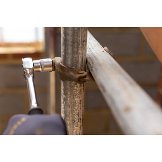 STANLEY FMMT17246-0 ratchet wrench tightening pipe clamp, close-up indoor construction setting.