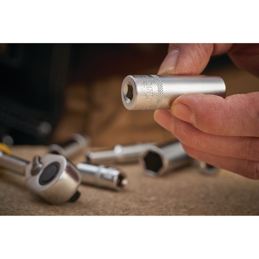 Photo of STANLEY FMMT17337-0 socket held in hand, with ratchet and sockets in background, close-up view.