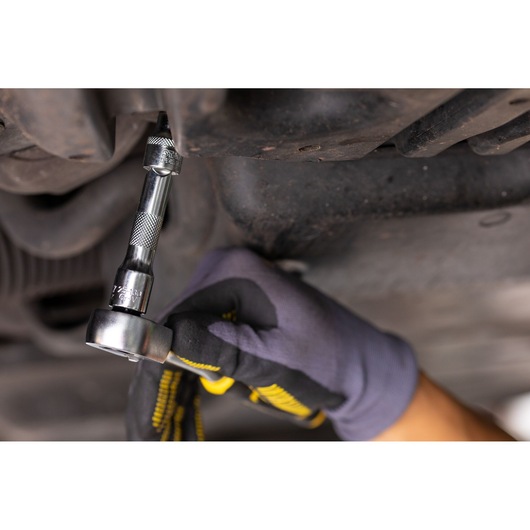 STANLEY FMMT25130-0 ratchet being used under a vehicle, close-up of gloved hand operating tool.