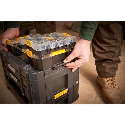 STANLEY FMMT98102-0 black and yellow stackable organizer being latched, photo shows hands and boots.