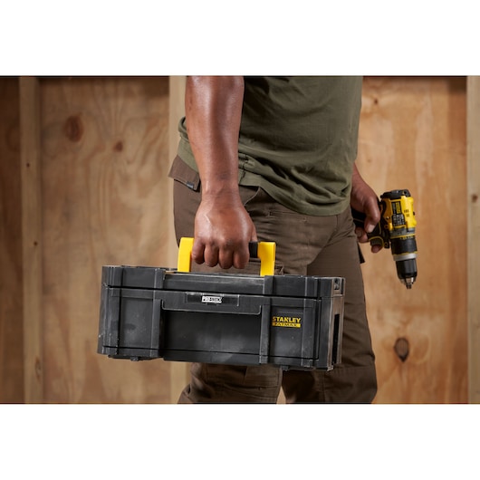 Photo of person holding STANLEY FMST1-71968 toolbox with yellow handle, product category Photography.