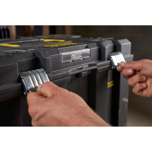 Photo of hands opening metal latches on STANLEY FMST1-75753 tool box, close-up view of front locking system.