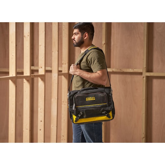 STANLEY FMST1-80149 black and yellow tool bag worn over shoulder on construction site.