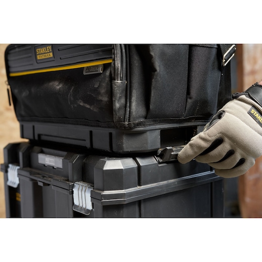 STANLEY FMST17627-1 tool box close-up, stacked modular cases, gloved hand securing latch, product side angle.