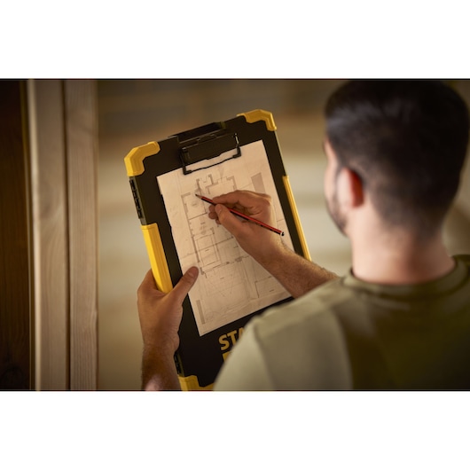 STANLEY FMST82721-1 clipboard held by person sketching on architectural plan, product photography.