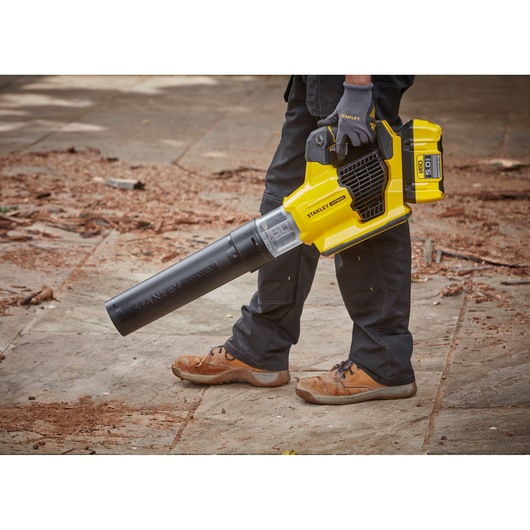 Photo of STANLEY SFMCBLB76B cordless leaf blower in use, yellow and black design, outdoor setting.