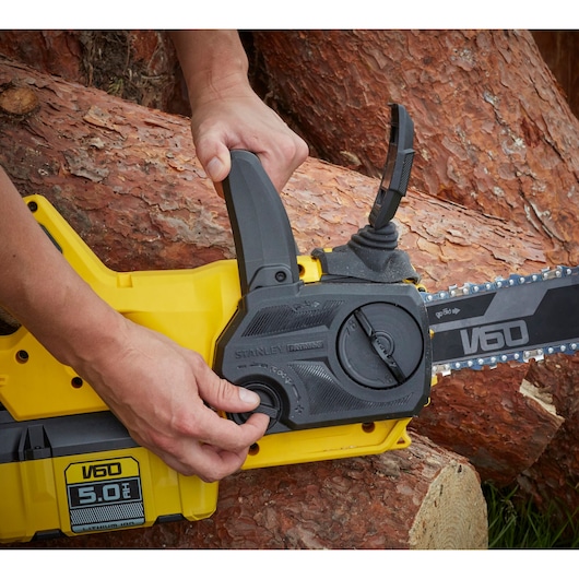 STANLEY SFMCCSB664B chainsaw with yellow and black housing, shown adjusting chain tension outdoors.