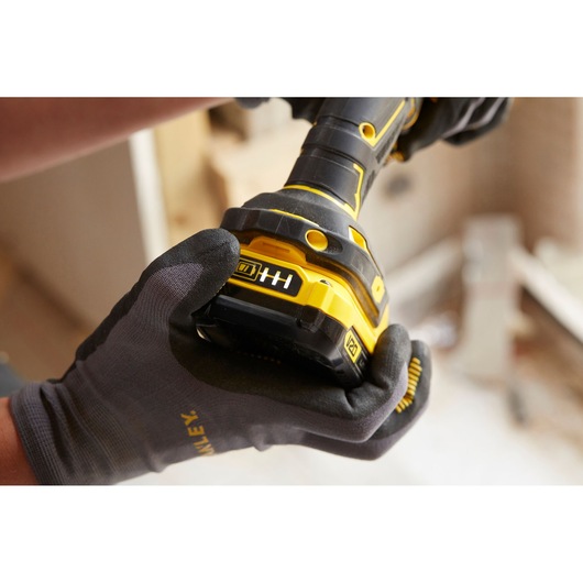 STANLEY SFMCD700C2K cordless drill close-up, gloved hand holding yellow and black tool, battery indicator visible.