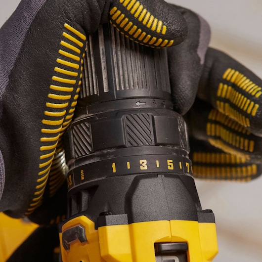 STANLEY SFMCD700C2S drill close-up, yellow and black, gloved hand adjusting torque settings.