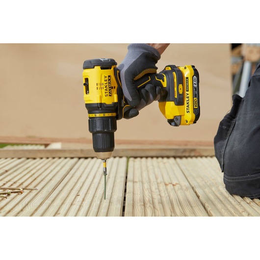 Stanley SFMCD710D2K cordless drill in use driving screw into wooden decking, side angle.