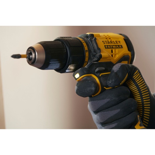 STANLEY SFMCD710D2K cordless drill, yellow and black, close-up view in gloved hand.