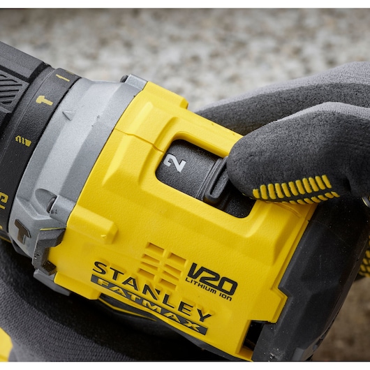 Photo of STANLEY SFMCD715C2K V20 FATMAX cordless drill close-up, glove hand adjusting speed switch.