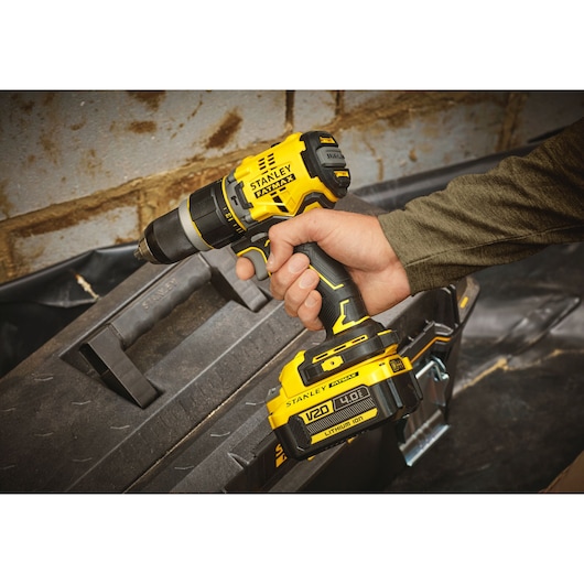 Stanley SFMCD721M2K cordless drill with V20 4.0Ah battery held in hand, photographed on construction site.