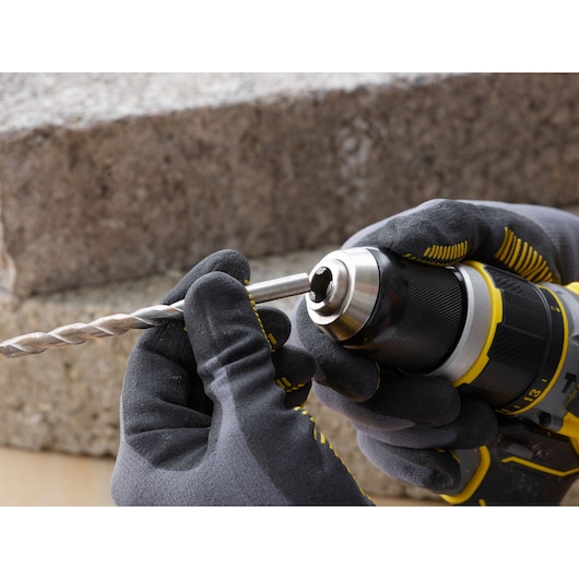 STANLEY SFMCD721M2K drill photography, close-up of gloved hands inserting a metal drill bit.