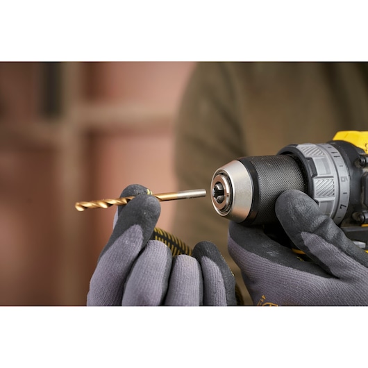 Photo of STANLEY SFMCD725B drill being fitted with a drill bit, close-up view with gloved hands.