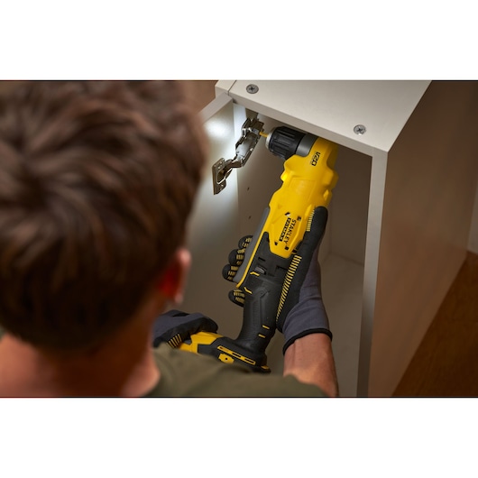 Photo of STANLEY SFMCD750B cordless drill being used inside a cabinet, close-up view.