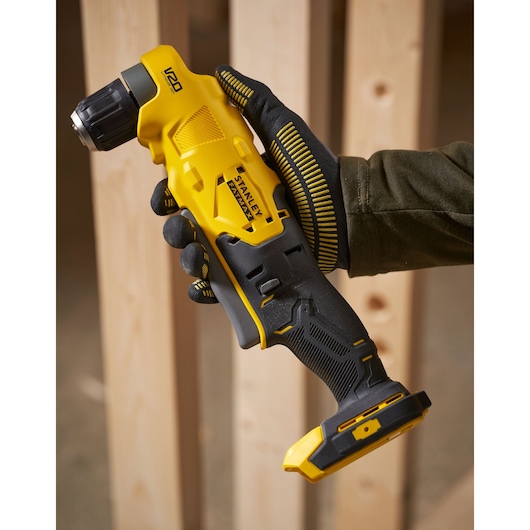 Stanley SFMCD750B cordless right angle drill in yellow and black, held in gloved hand, construction setting.