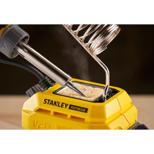 STANLEY SFMCE040B soldering station with soldering iron tip cleaning on yellow base, close-up angle.