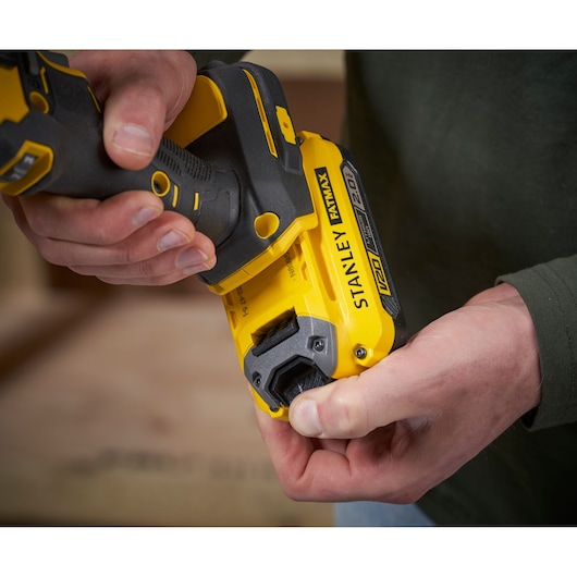 Photo of STANLEY SFMCE210B cordless tool, yellow and black, close-up showing battery installation.