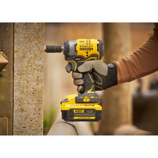 Photo of STANLEY SFMCF910B impact driver in use, yellow and black design, V20 4.0Ah lithium ion battery.