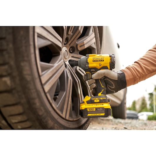STANLEY SFMCF920B cordless impact wrench used on car wheel, close-up outdoor.