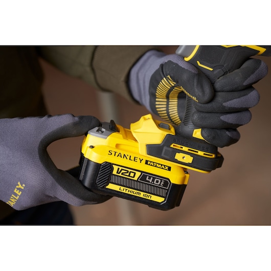 Photo of STANLEY SFMCF940B V20 4.0Ah lithium-ion battery being attached to a cordless tool, close-up view.