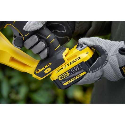 Stanley SFMCHT855B brushless trimmer close-up with V20 4.0Ah battery, yellow and black design.