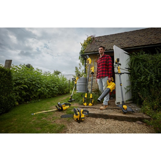 STANLEY SFMCHT855M1 garden tools group shot outdoors, featuring hedge trimmer, chainsaw, blower, and string trimmer.