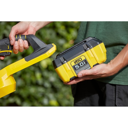 STANLEY SFMCHTB866B yellow and black V60 5.0Ah battery held near cordless tool outdoors