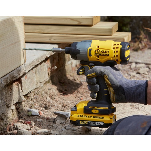 STANLEY SFMCK465D2S cordless impact driver in use driving screw into wood, showing battery and grip details.